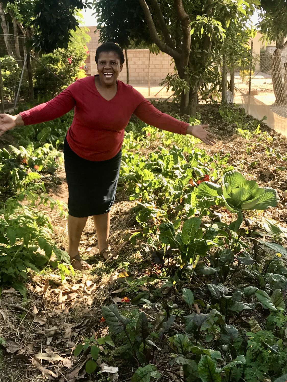 Woman in red top posing in a garden